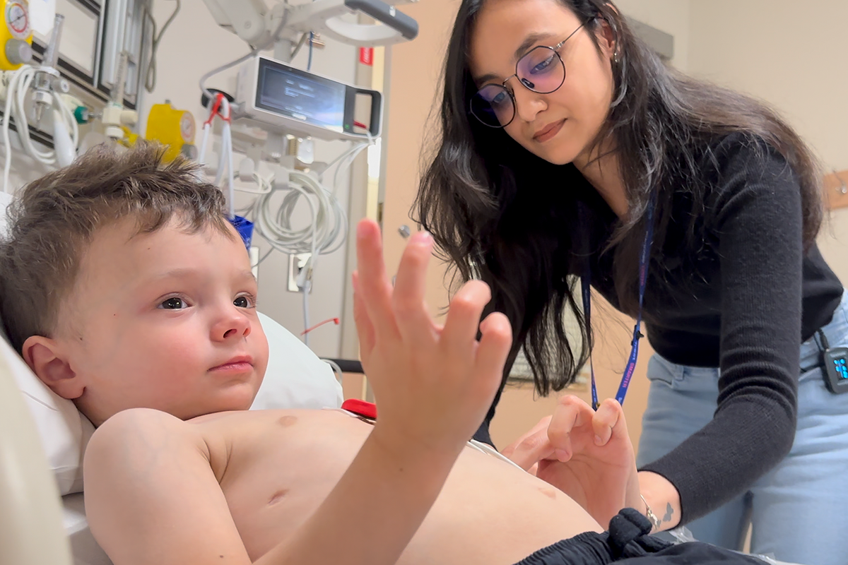 A Clinical Research Associate works with a young boy in a clinical trial at SickKids.