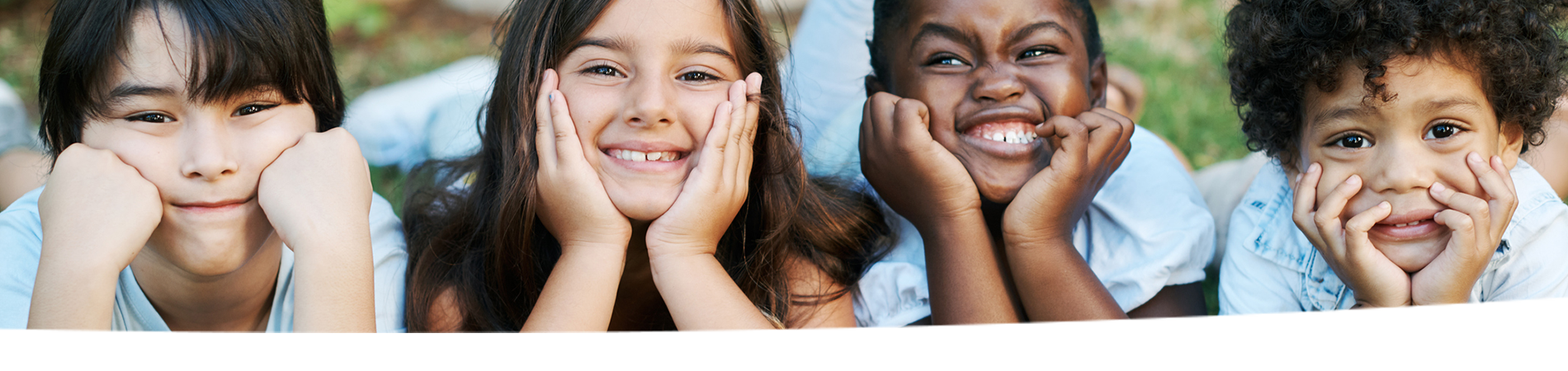 Four kids lay in the grass.