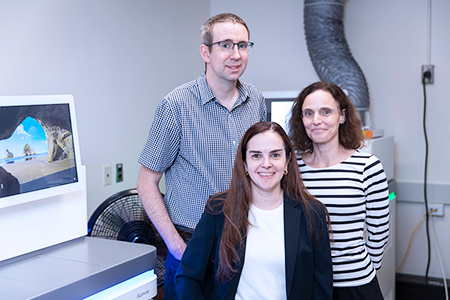Three researchers stand infront of a clinical RNA sequencer at SickKids.