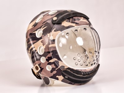 A camouflage-printed custom protective helmet sits in front of a white background. 