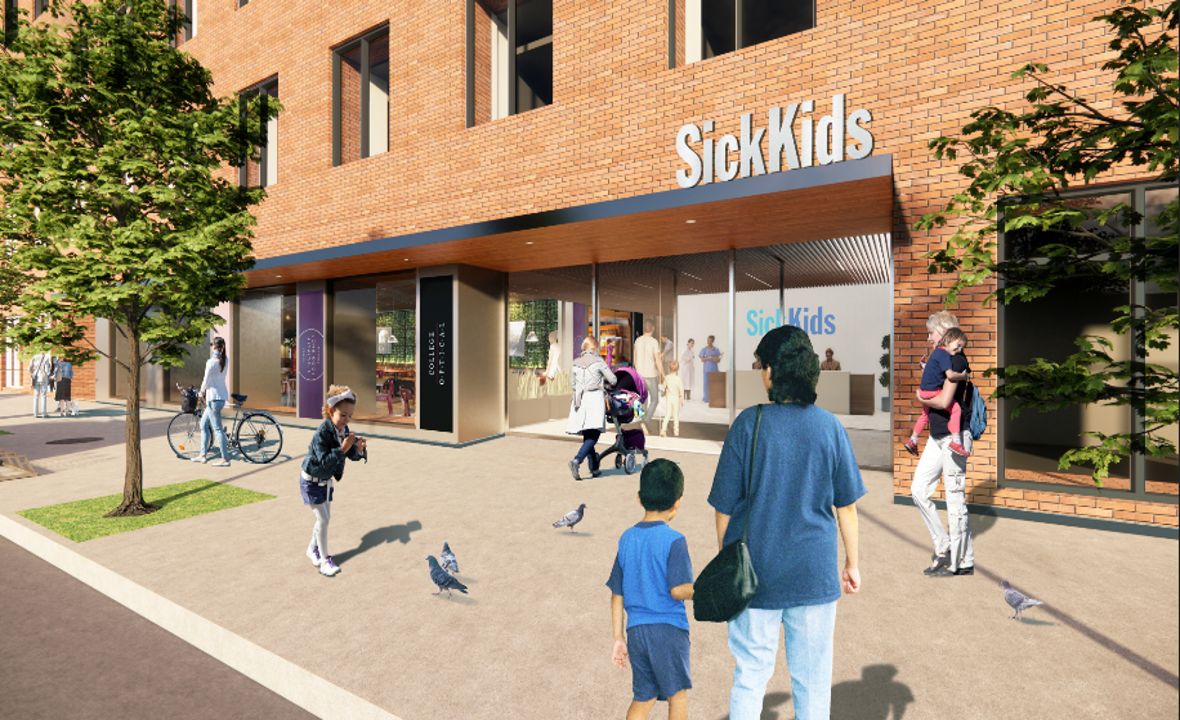People walk toward a brick building with a SickKids sign, while children play and families gather near the entrance.