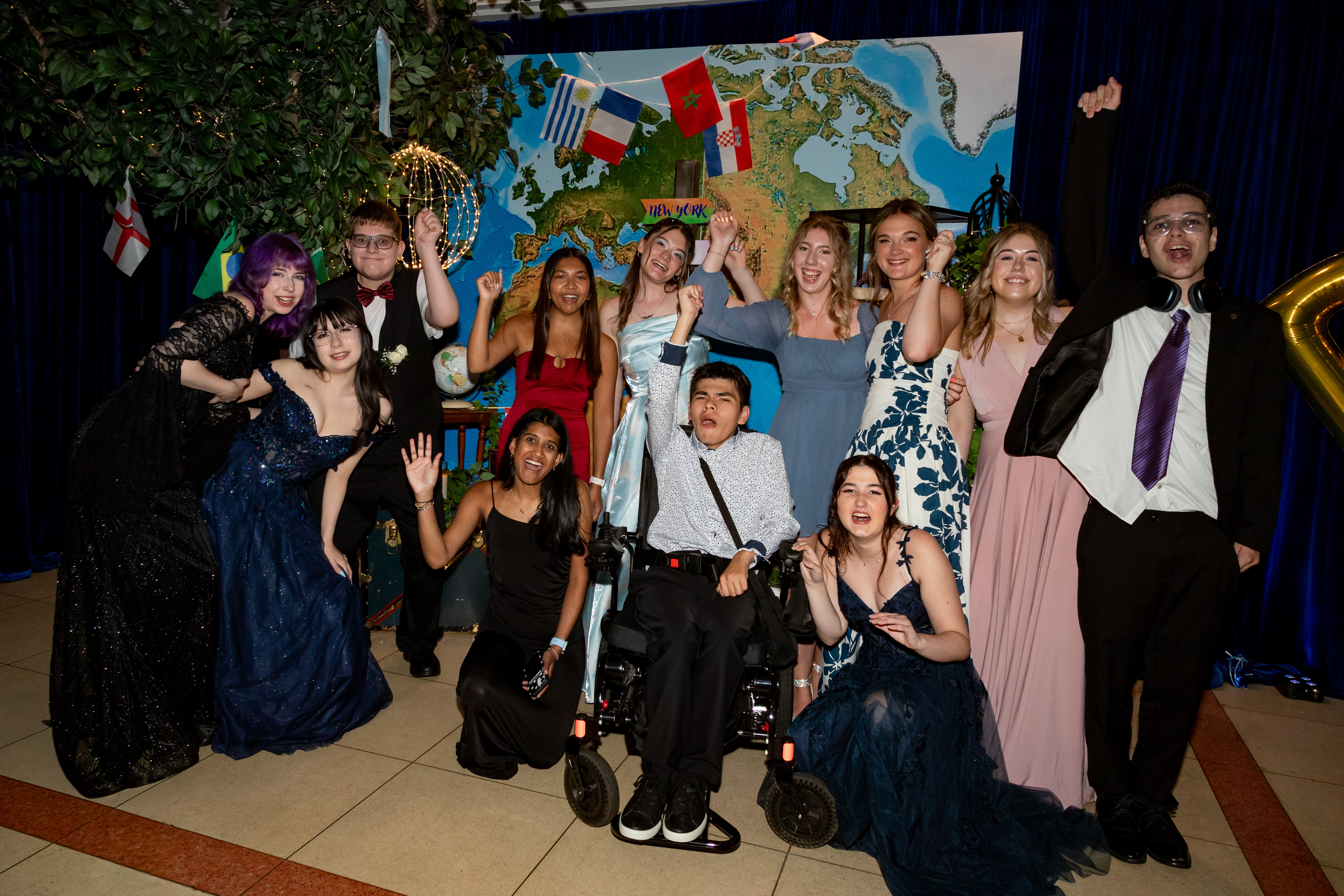 A group of patients and guests smile and hold up their hands in front of a map backdrop.