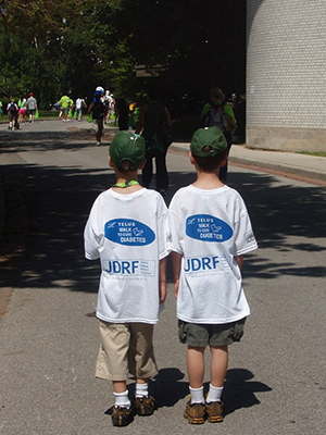 Two boys walk down a road, both wearing t-shirts supporting research for type 1 diabetes.