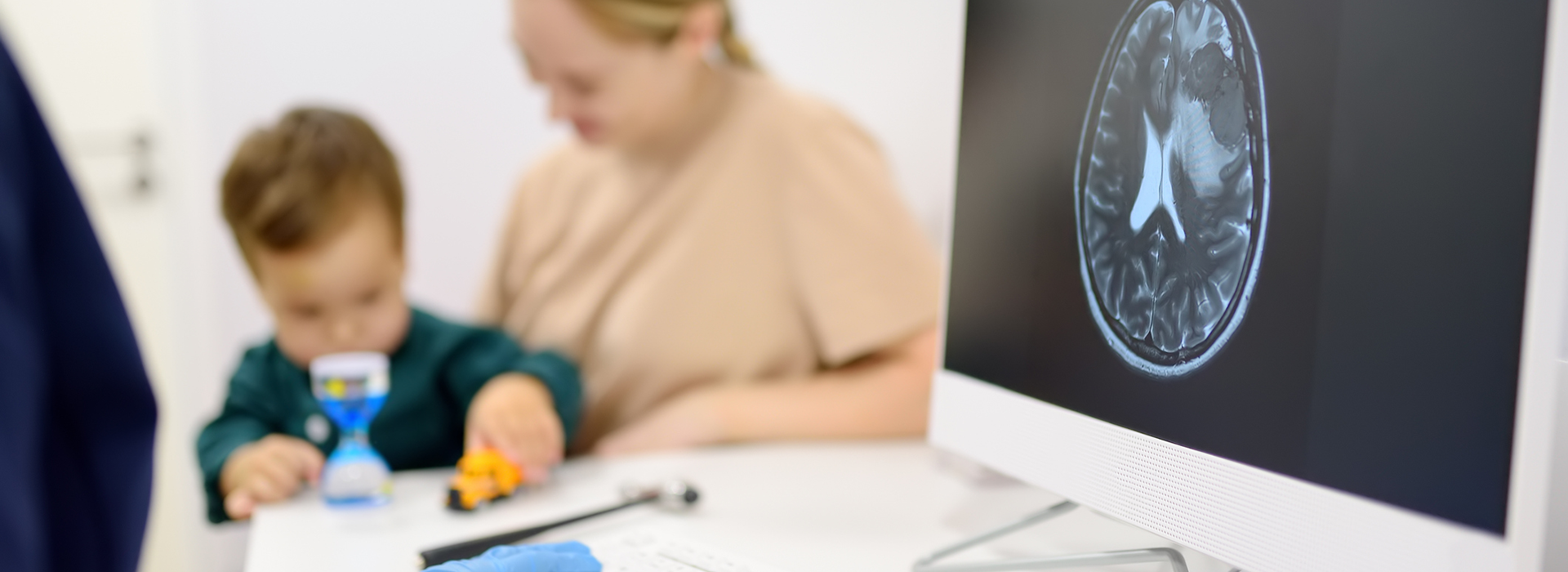 A parent and child sit with a physician examining a scan of the child's brain. 