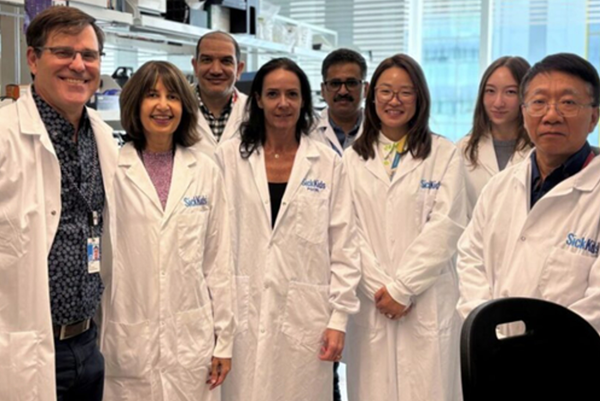 Seema Mital stands in a research lab with members of lab team in lab coats