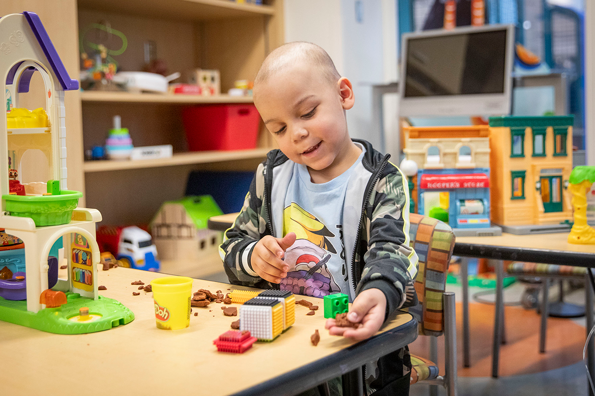 A young boy plays with clay in a waiting room at SickKids.