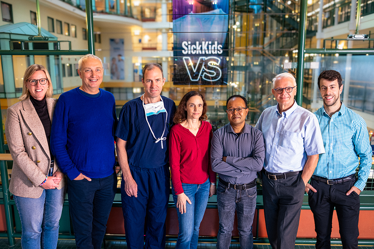 Seven scientists and clinicians smiling in SickKids hospital.