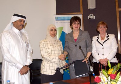 Four professionals at formal event - Arab man in traditional dress, woman in hijab, two women in business suits.