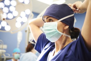 Woman in medical scrubs tying PPE mask around her head