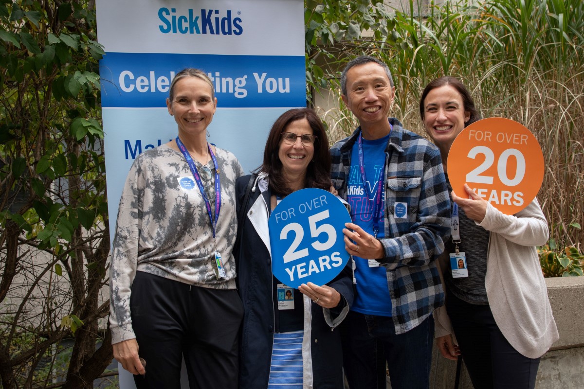 Staff members stand together holding props showing years of service.