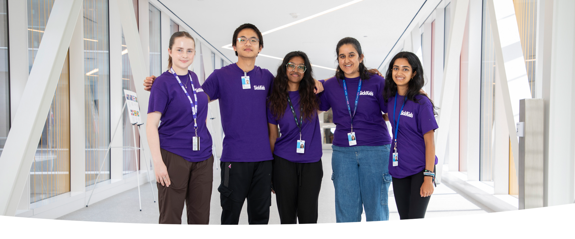 Five youth wearing purple t-shirts stand together smiling.