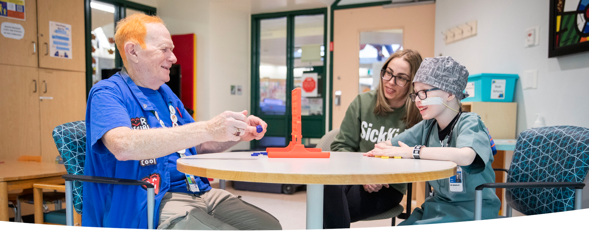 Volunteer plays a board game with a patient and parent.