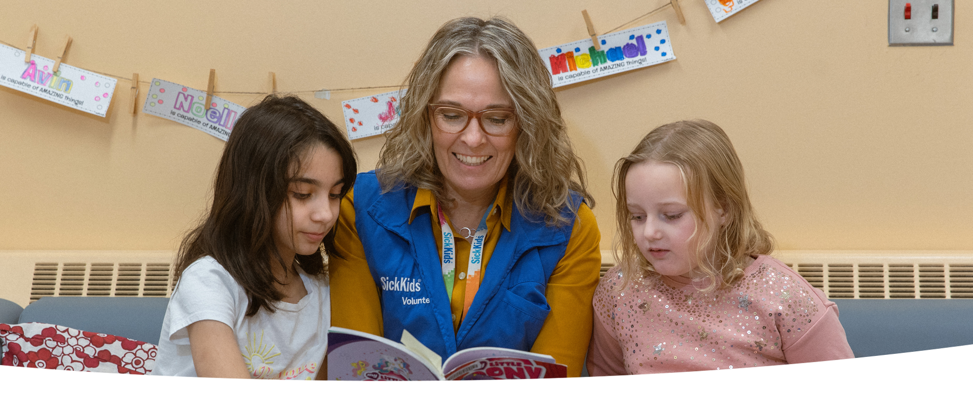 Volunteer reads a book to two children.