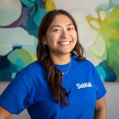 Teen in blue volunteer shirt smiles at the camera.