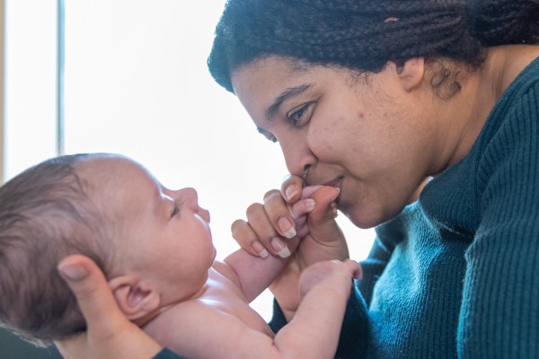 Closeup of mom kissing an infant's hands in a hospital room