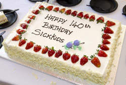 Birthday cake with strawberries and writing that reads "Happy 140th Birthday SickKids"