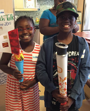 Two kids holding torches; one is a small replica, the other is the actual pan am torch