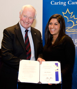 A man and woman stand together smiling and displaying two framed pieces of paper