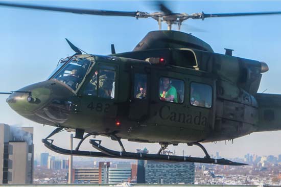 A Canadian Air Forces helicopter flying in the air, with men dressed as elves inside