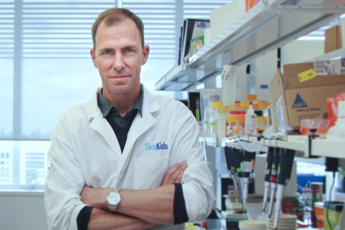 Peter Dirks standing against a laboratory bench, surrounded by lab equipment
