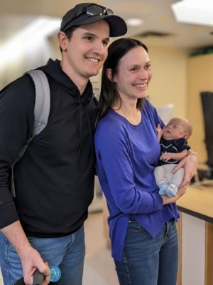 Brett stands beside Erica, who is holding Jeff.