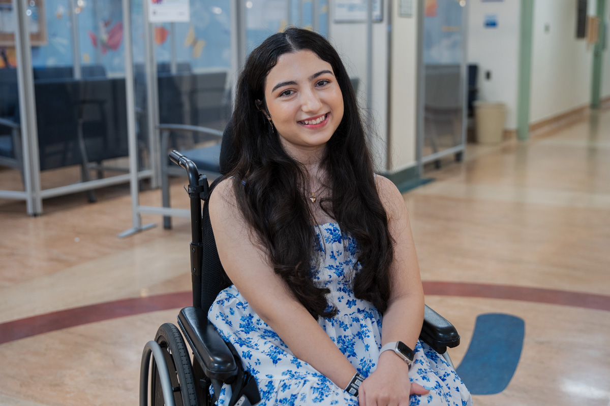 Melika in a wheelchair posing for a photo in a clinic hallway