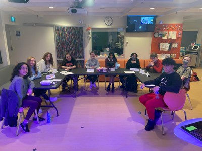 Ten youth sitting around tables set up in a semi-circle.