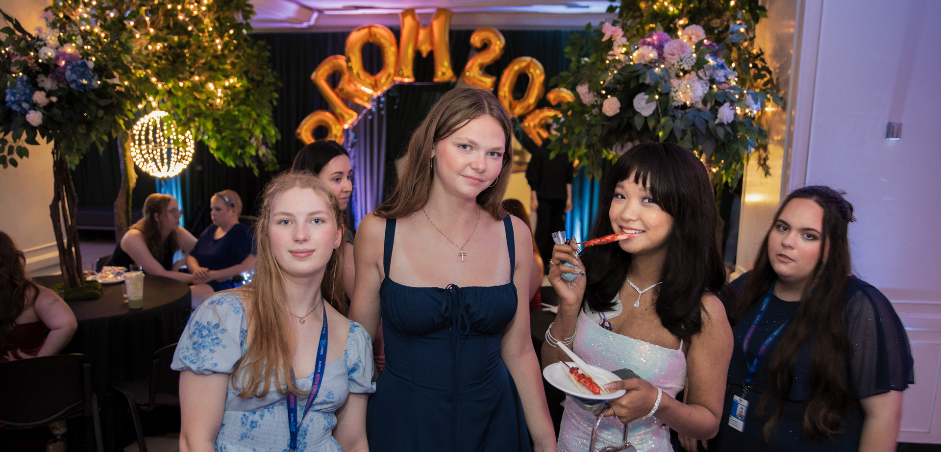 Four SickKids prom attendees posing for a photo. One of them is enjoying a dessert.