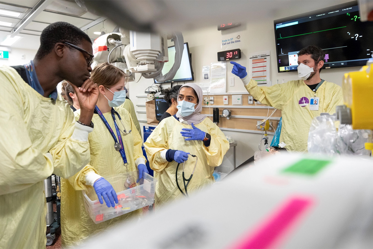 A care team conversing with each other and assessing their simulated patient in the trauma room