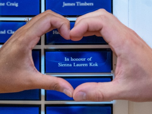 Brittany and Tyler's hands form a heart over a blue plaque that reads "In honour of Sienna Lauren Kok."