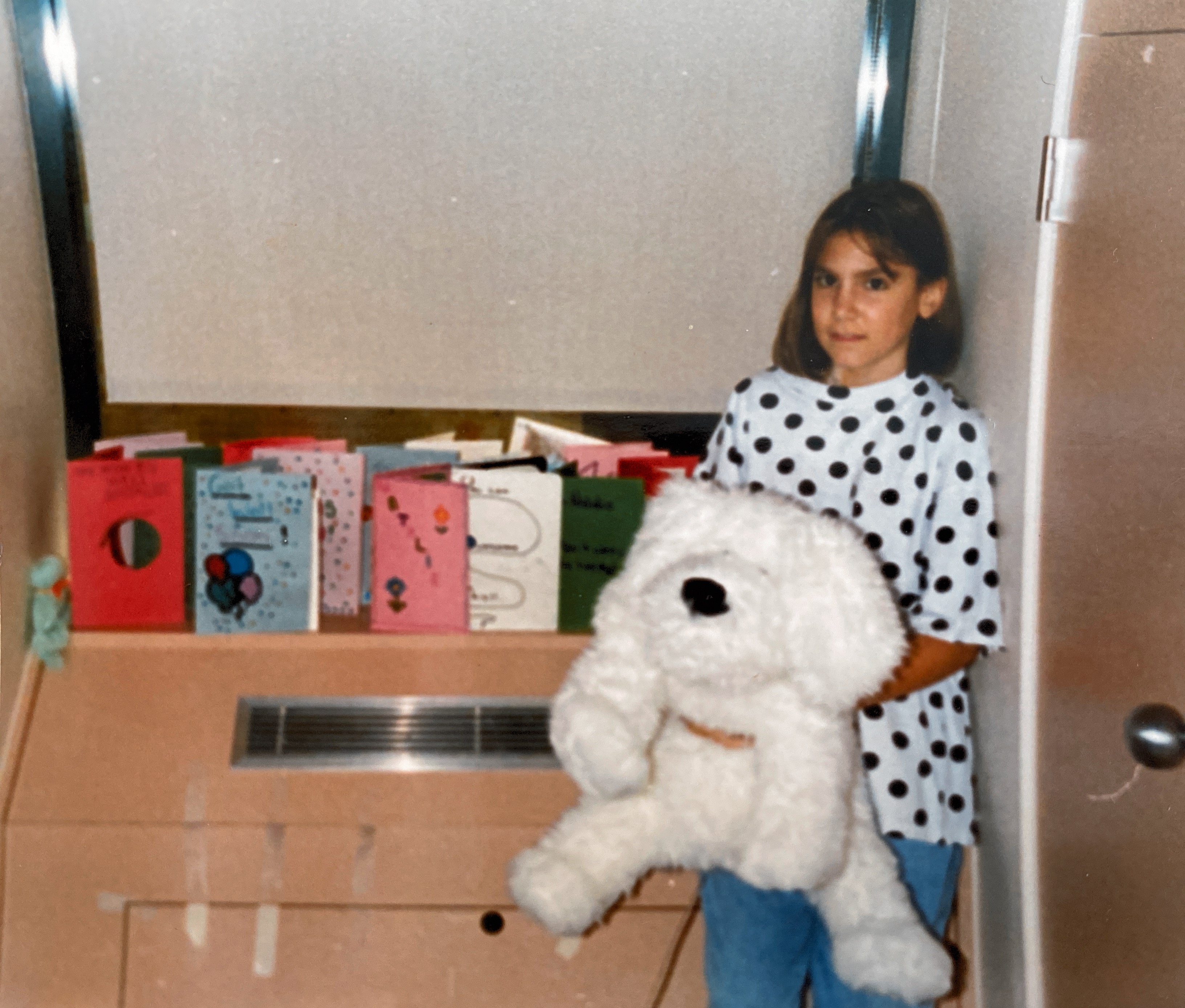 Natalie holding a white stuffed animal with lots of cards in her room.