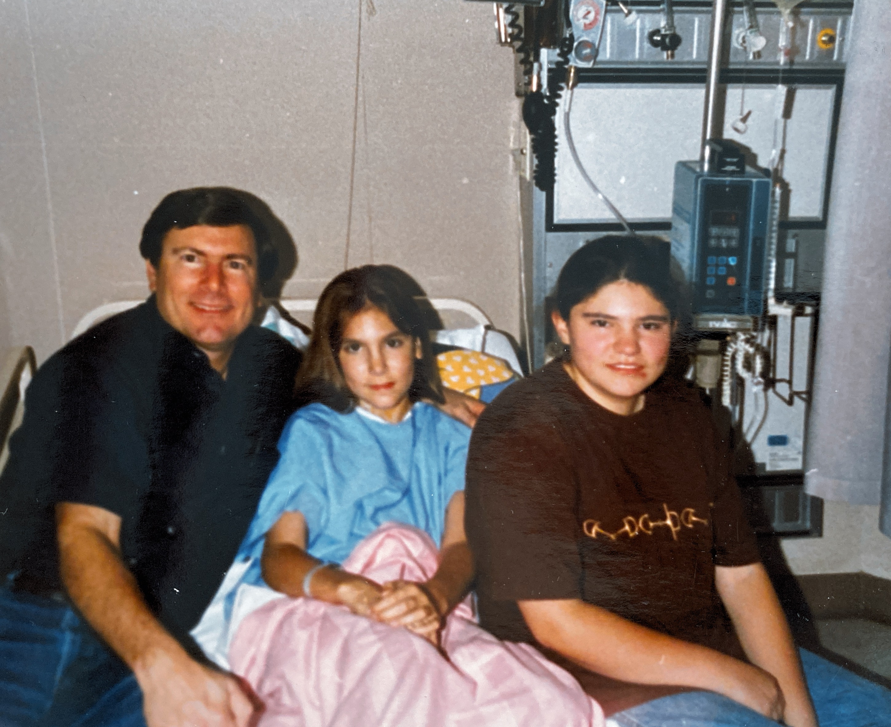 Natalie in a hospital bed with her sister and dad.