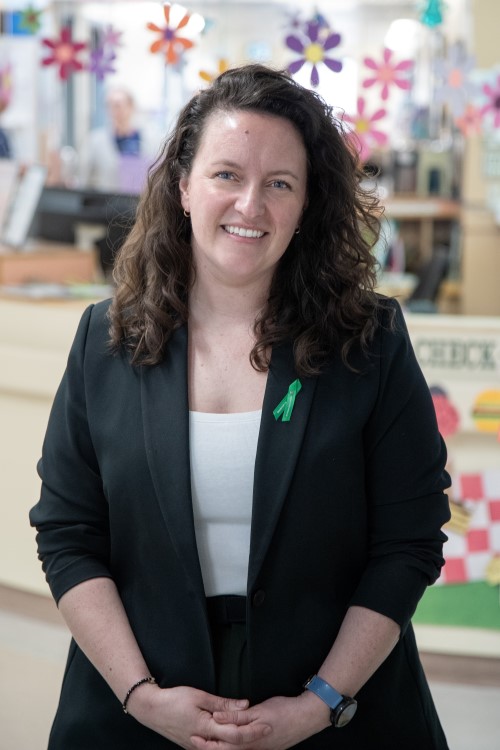 Kalyn Bolland stands smiling in front of a clinic desk with flower decorations hanging above her head.
