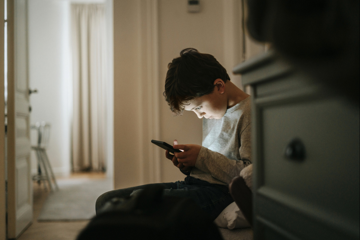 Child sitting and looking at smartphone